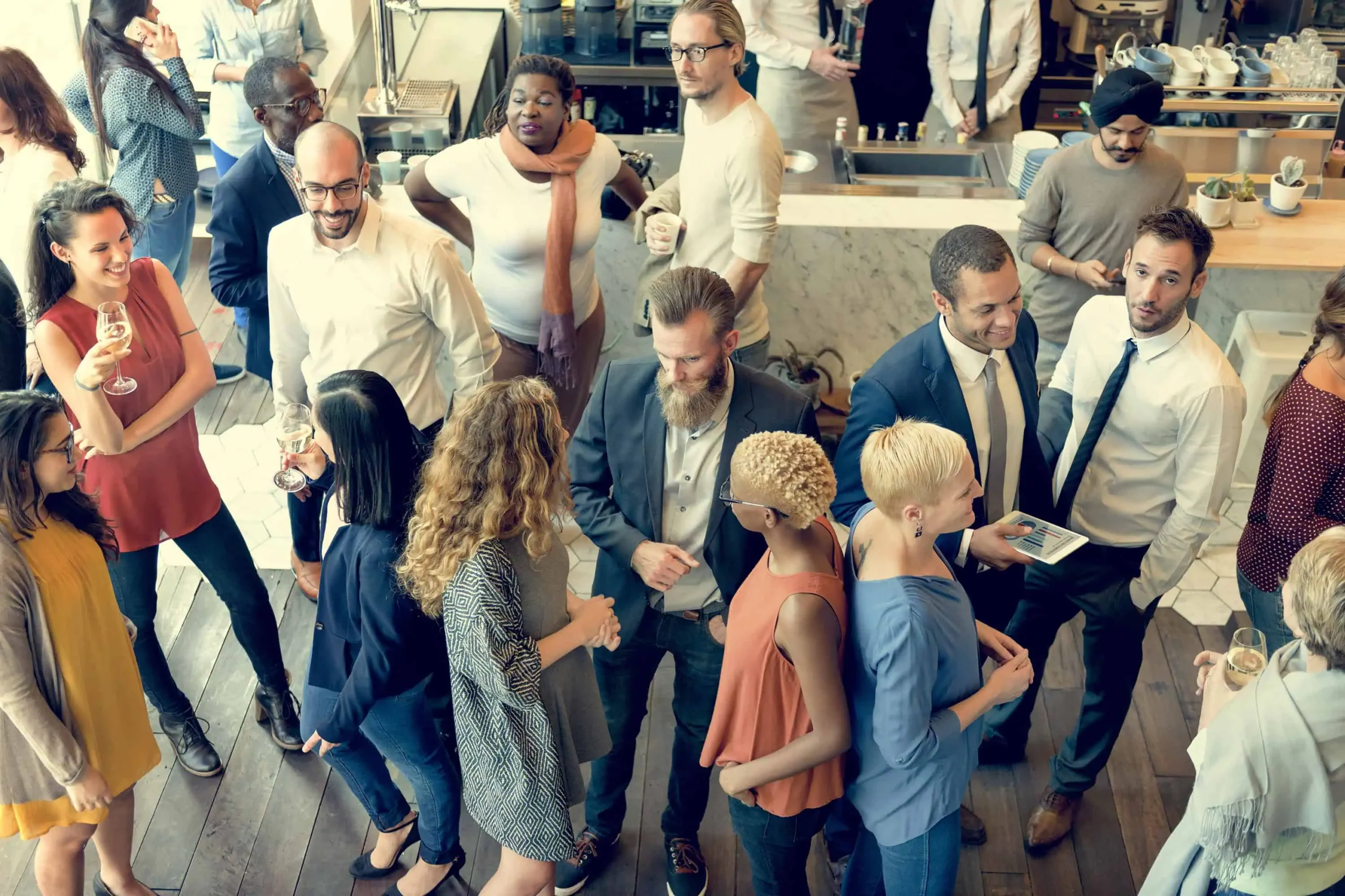 Grupo de personas interactuando en un evento social en un café, con conversaciones animadas y networking profesional.